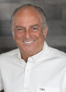 A smiling man showcasing his experience in a white shirt.